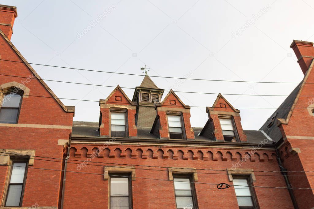 Red brick facade on residential urban apartment building with dormers and cupola, horizontal aspect
