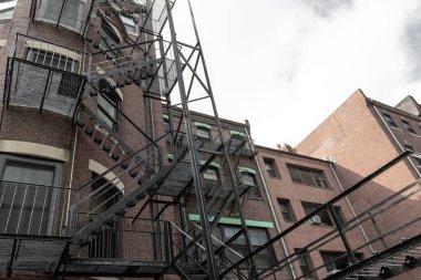 Metal yangın merdivenleri, eski tuğla apartmanın dış tarafında, yatay açıda.