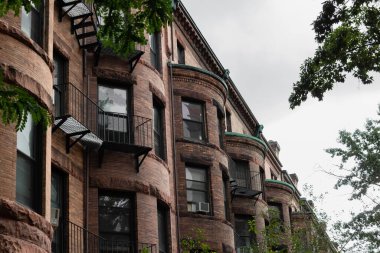 Yarım yuvarlak cepheli, metal bacalı ve oksitlenmiş olukları, yatay görünümlü eski kahverengi apartman dairelerine bakın