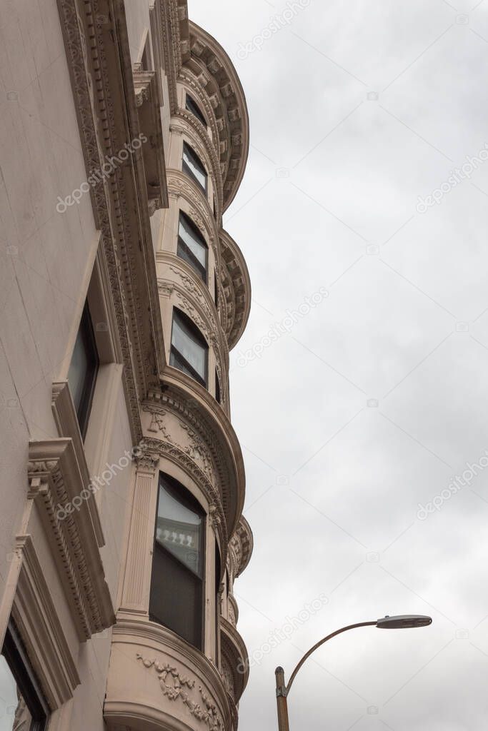 View of bowed front brownstone with layers of ornate mouldings, vertical aspect