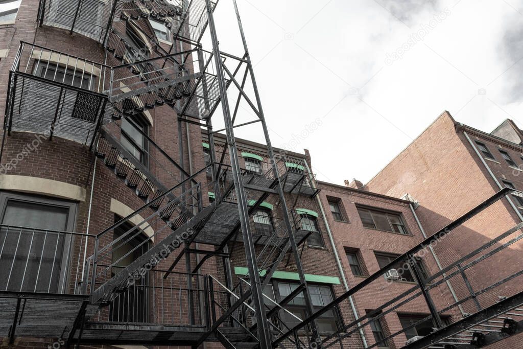 Layers of metal fire escapes on the exterior rear of old brick apartment building, horizontal aspect