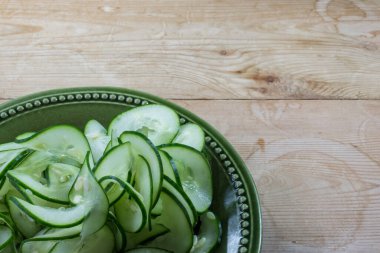 Yemyeşil seramik bir kase sarmal kurdele parçalanmış salatalıklar yıpranmış ahşap bir masa üzerinde, kopya alanı, yatay görünüm