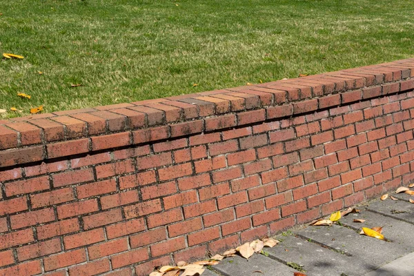 Toprak lekeli harç, yeşil çimen ve beton yatay görünümlü tuğla istinat duvarı