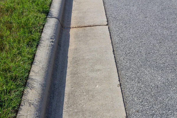Yeşil çimen ve asfalt sokak arasında genel beton kaldırım oluşturulmuş, yatay görünüm