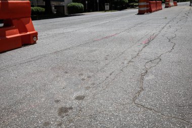Trafik fıçıları ile turuncu ve beyaz plastik barikatlar arasında açık alan olan çatlak asfalt sokak, yaratıcı kopya alanı, yatay görünüm