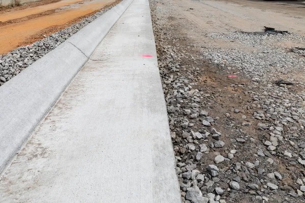 Çıkan beton kaldırım, çakıllı, çamurlu, yatay görünümlü sokak inşaatı detaylarını doğrudan incele.
