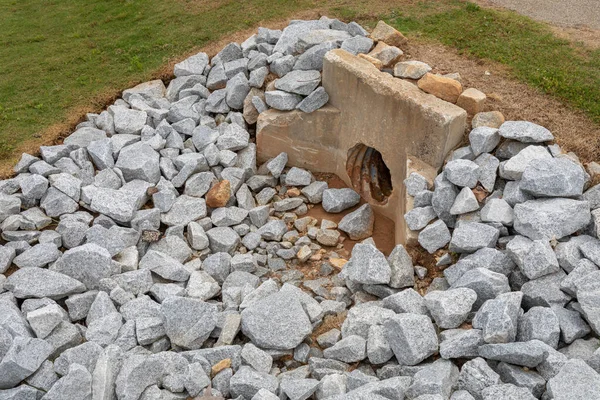 Yeni granit kaya sulama ve erozyon kontrolü ile çevrili eski döküm beton başlık, yeşil çimen, menfez aşınma gelişimi, yatay görünüm