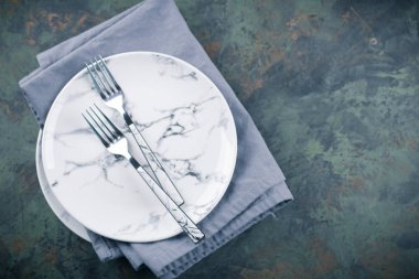 Çatallar ve mavi yeşil mermer masa peçete ile şık seramik plakalar