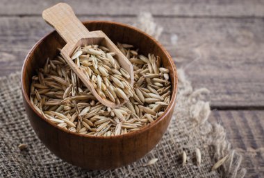 Eski ahşap masa üzerinde kepçe ile ahşap kase yulaf kabuğu çıkarılmış tane