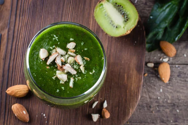 Fresh green smoothies with kiwi and almond on wooden table