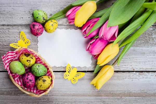 Желтые Розовые Тюльпаны Разноцветными Перепелиными Яйцами Белой Карточкой Деревянном Столе — стоковое фото