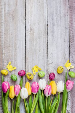 Lale ve renkli bıldırcın Paskalya kompozisyonu eski püskü ahşap arka plan üzerinde yumurta