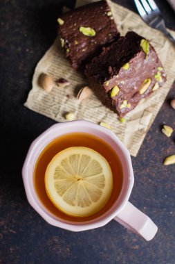 Çay limon ve nane ile taş masanın üzerine Antep fıstığı ile bisküvi kek ile hizmet bırakır