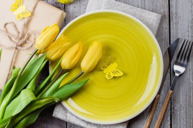 Paskalya sofra laleler, renkli bıldırcın yumurtası ve eski püskü ahşap masa üzerinde hediye kutusu