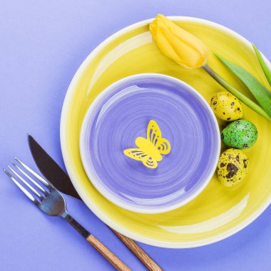 Paskalya sofra bahar laleler, renkli bıldırcın yumurtası ve mor zemin üzerine