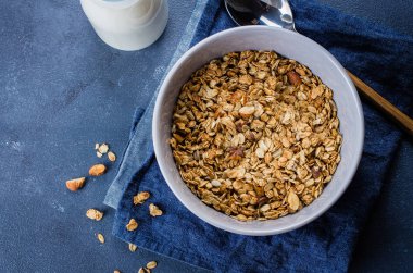 Plaka ev yapımı granola en iyi manzara mavi taş masada. Vejetaryen kahvaltı - granola, süt veya yoğurt için malzemeler. Metin için yer kopyalayın. Gıda sağlıklı arka plan.
