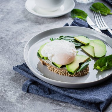 Avokado, ıspanak ve kepekli ekmek plaka taş zemin üzerine haşlanmış yumurta ile sandviç