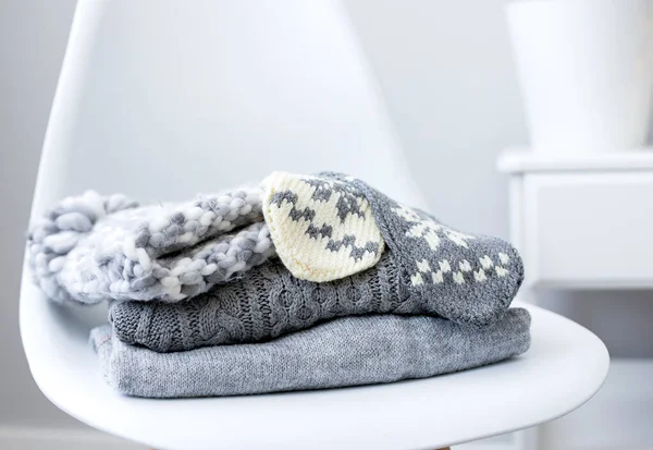 Une pile de pulls tricotés et accessoires sur chaise à l'intérieur du salon — Photo