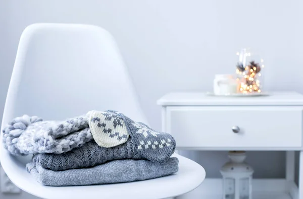 A stack of knitted sweaters and accessories on chair in Interior of the living room — Stock Photo, Image