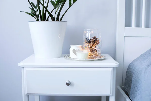 Christmas decor on the bedside table near the bed in the bedroom. Cozy interior details, soft and warm home decor. — Stock Photo, Image