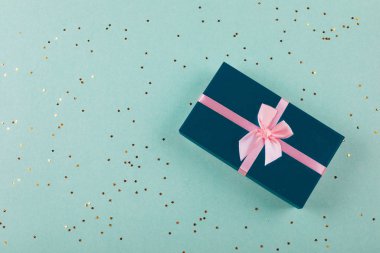 Nane arkaplanda altın parıltılı koyu mavi bir hediye kutusu. Noel, doğum günü, tatil konsepti. Üst görünüm, düz görünüm, kopyalama alanı