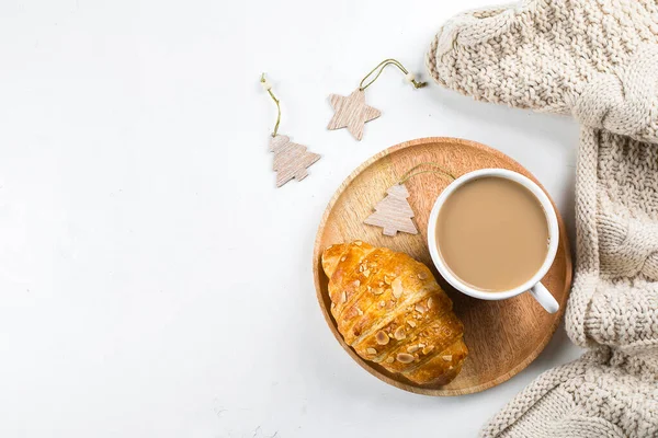 Acogedor desayuno de Navidad piso laico. Taza de café, croissant y suéteres acogedores sobre fondo de mesa blanco. Vista superior, espacio de copia — Foto de Stock