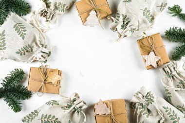 Noel hediyesi yatıyordu. Sıfır Atık Hediye Paketleme Tatil Sezonu Çevre dostu Yaşam Tarzı. Beyaz arka planda köknar dalı olan el işi kutuları ve çantalar. Üst görünüm, düz görünüm, kopyalama alanı