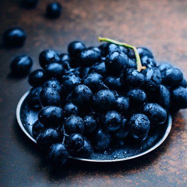 Metal tepsi dokuma sehpasında taze olgun mavi üzümler. Koyu üzüm, mavi üzüm, şarap üzümü. Kırpma resmi