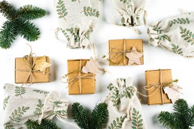 Noel kompozisyonu, beyaz arka planda köknar dalı olan el sanatları kutuları ve keseler. Sıfır Atık Hediye Paketleme Tatil Sezonu Çevre dostu. Üst manzara, düz uzanma