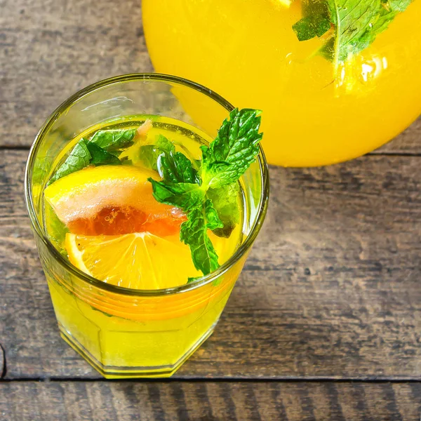 Limonada cítrica de verano con naranja, pomelo y menta en un vaso sobre una mesa rústica de madera. Recortar imagen cuadrada — Foto de Stock