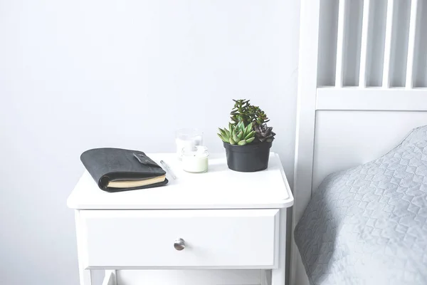 Tiny succulents, candles and black notebook on bedside table in — Stock Photo, Image