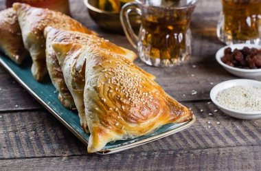 Doğu mutfağı. Etli lezzetli samosas samsa, ahşap masa arkasında bir bardak çay. Ramazan yemekleri
