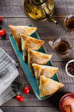 Doğu mutfağı. Etli leziz samosas samsa, ahşap masa arkasında bir bardak çay, üst manzara. Ramazan yemekleri