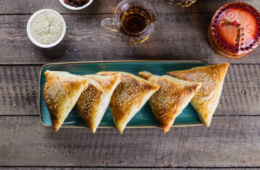 Doğu mutfağı. Etli leziz samosas samsa, ahşap masa arkasında bir bardak çay, üst manzara. Ramazan yemekleri