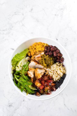 Meksika yemek kasesi mermer arka planda. Mısır ile salata kasesi, kırmızı fasulye, kırmızı soğanlı domates, jalapenyo, tavuk göğsü. Üst görünüm, alanı kopyala