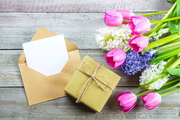 Mockup Mother's day Concept. Spring flowers tulips and hyacinth, gift box and empty card on shabby wooden background. Greeting card for Womens or Mothers Day. Flat lay, top view, copy space. — Stockfoto
