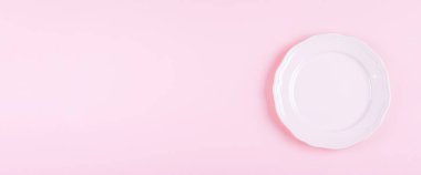 Pembe masa arkasında açık pembe bir tabak. Mutfak tabağı. Tarif Menüsü Konsepti. Web sitesi afişi. Üst görünüm, düz görünüm, kopyalama alanı