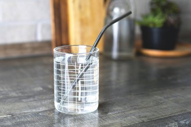 Mutfak masasında metal pipetli bir bardak su. Eko natura