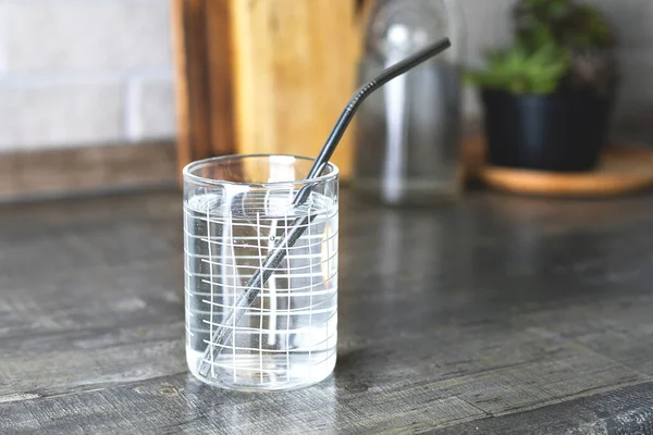 Glass of water with metallic straws on kitchen table. Eco natura