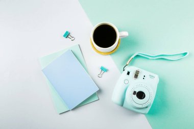Flat lay with modern mini camera, two notebook and cup of coffee on double grey green background. Top view, flat lay style composition. Fashion blogger, minimal concept.