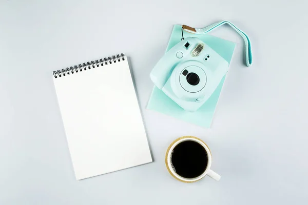 Flat lay com mini câmera moderna, notebook vazio e xícara de café em fundo cinza. Vista superior, composição de estilo leigo plana. Blogueiro de moda, conceito mínimo . — Fotografia de Stock