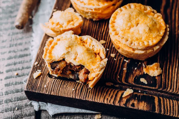 Färsk traditionell australisk kött mini paj på träskiva på bordet bakgrund, närbild med kopia utrymme, rustik stil — Stockfoto