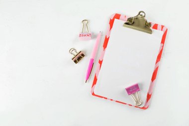 Düz moda kadınsı ofis çalışma alanı beyaz masa arkasında boş kağıt pano, kalem ve klipslerle yatıyordu. Üst Manzara. kopyalama alanı. Model konsepti