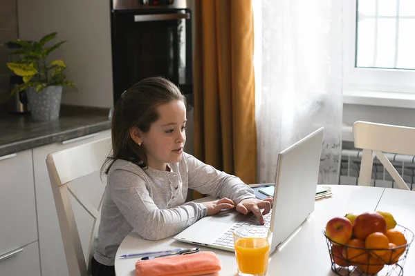 Pretty cute schoolgirl studying at home using laptop. Coronavirus home school, online education, home education, quarantine concept. Social distance during quarantine, self-isolation concept.