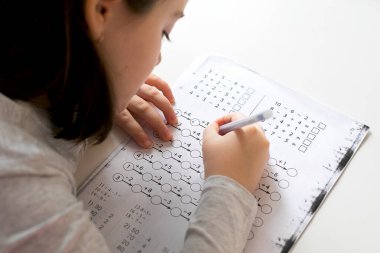 7-8 yaşlarında, evde ders çalışan sevimli bir kız. Ev okulu, internet eğitimi, ev eğitimi, karantina, koronavirüs konsepti