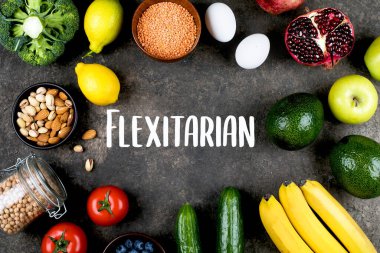 Flexitarian Diyet Konsepti. Yeşil sebzeler, domatesler, fındıklar, meyveler, mercimekler, nohutlar, koyu yeşil masa arkaplanı. Düz yerde, üst tarafta. Metin, model konsepti için yeri olan yiyecek çerçevesi