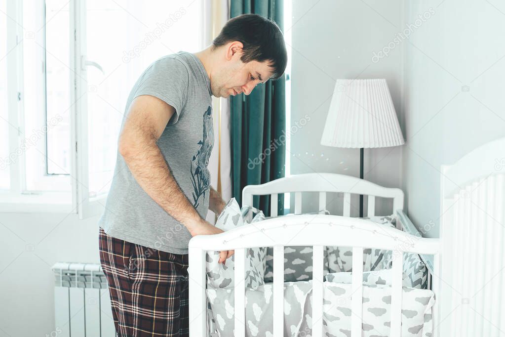 Father helps young mother put on bumpers in the crib. Family lifestyle concept