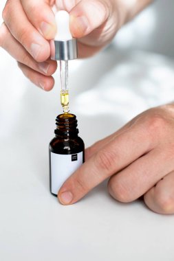Erkek ellerinde gerekli yağ ve şişeden bir damla Pipette. Güzellik, doğal kozmetik konsepti. Alternatif tıp