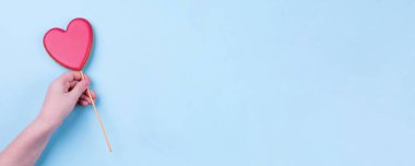 Pembe kalbi tutan el. Tatlı kurabiyeler kalbi şekillendirir. Tatil, tebrik kartı konsepti. Mavi pastel arka plan. Üst görünüm, düz görünüm, kopyalama alanı. Sancak resmi