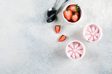 Açık beton masa arkasında kasede çilekli dondurma. Yaz tatlısı. Üst görünüm, kopyalama alanı, düz uzanma.